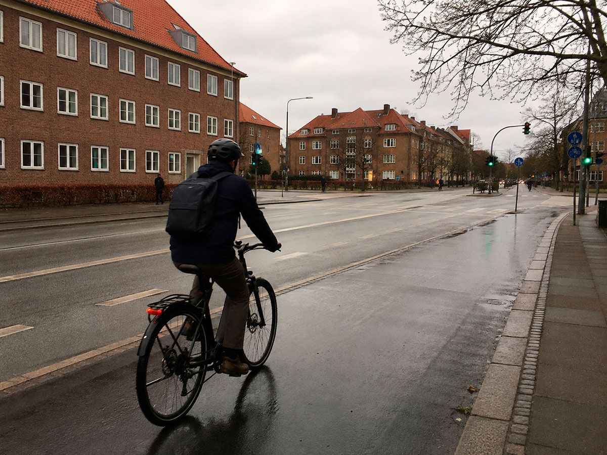 Cyklist der pendler i regnvejr med cykelhjelm